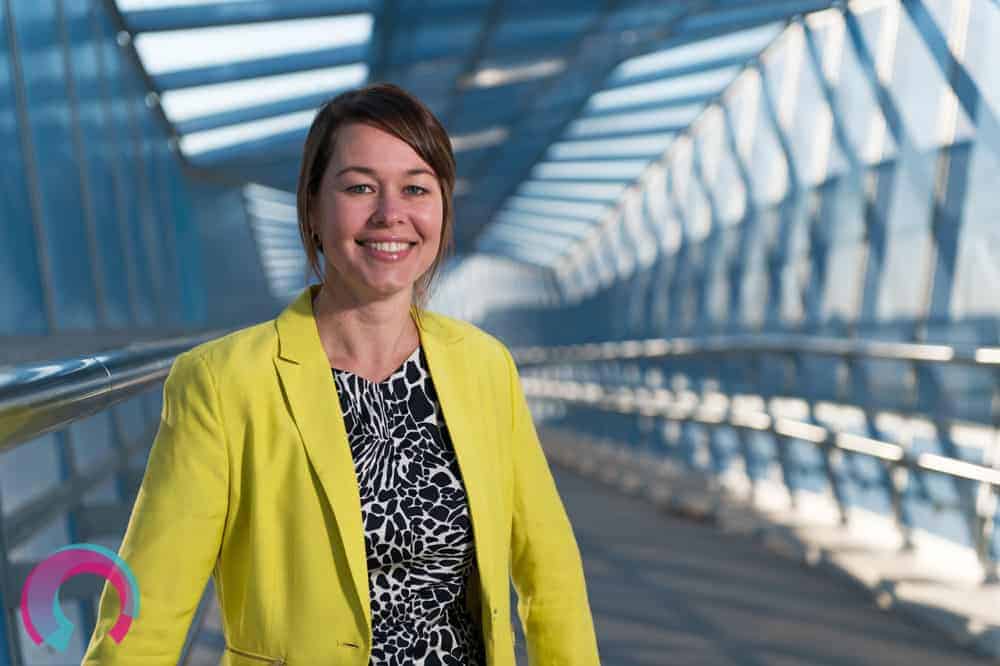 Brisbane commercial portrait photographer - Portrait image of woman in yellow jacket with architectural detail behind her (Ipswich Motorway Overpass, blue steel structural detail)