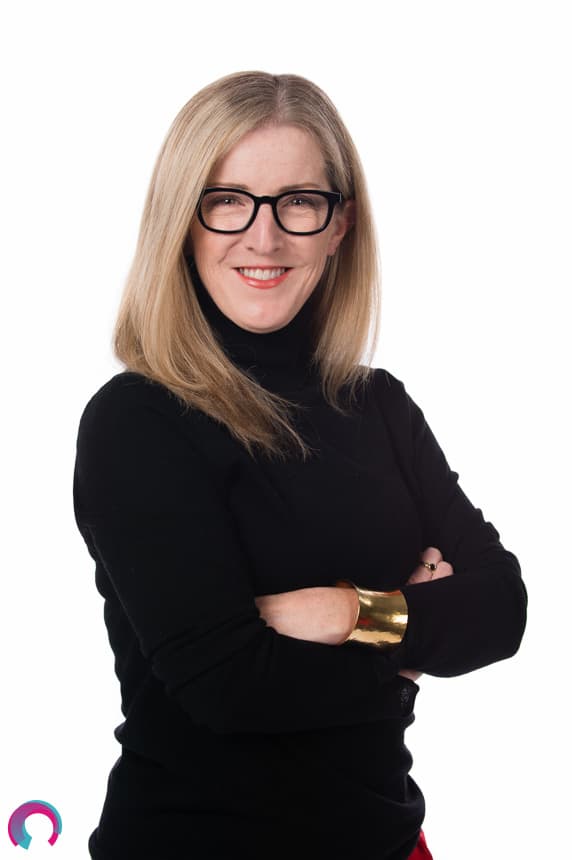 Corporate portrait of a female Brisbane executive cropped at the waist, black shirt arms folded smiling. 