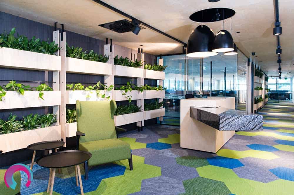 Reception area for commercial office showing geometric shapes and lovely marble reception desk, with hanging pendant lights. Wall of green plants behind reception desk - commercial office photography Brisbane