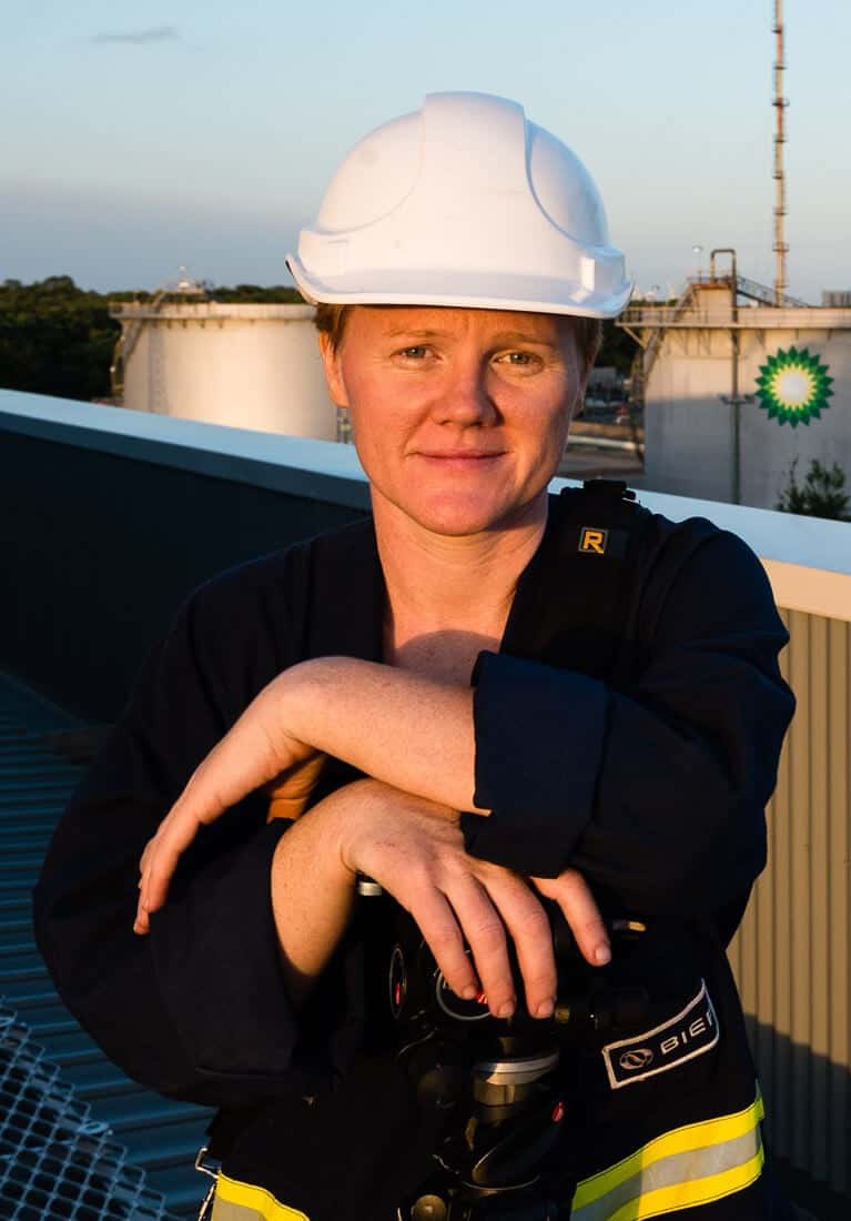 Portrait of industrial photographer and video producer, Jen Dainer, in safety hard hat and overalls, shot on an industrial site in Brisbane